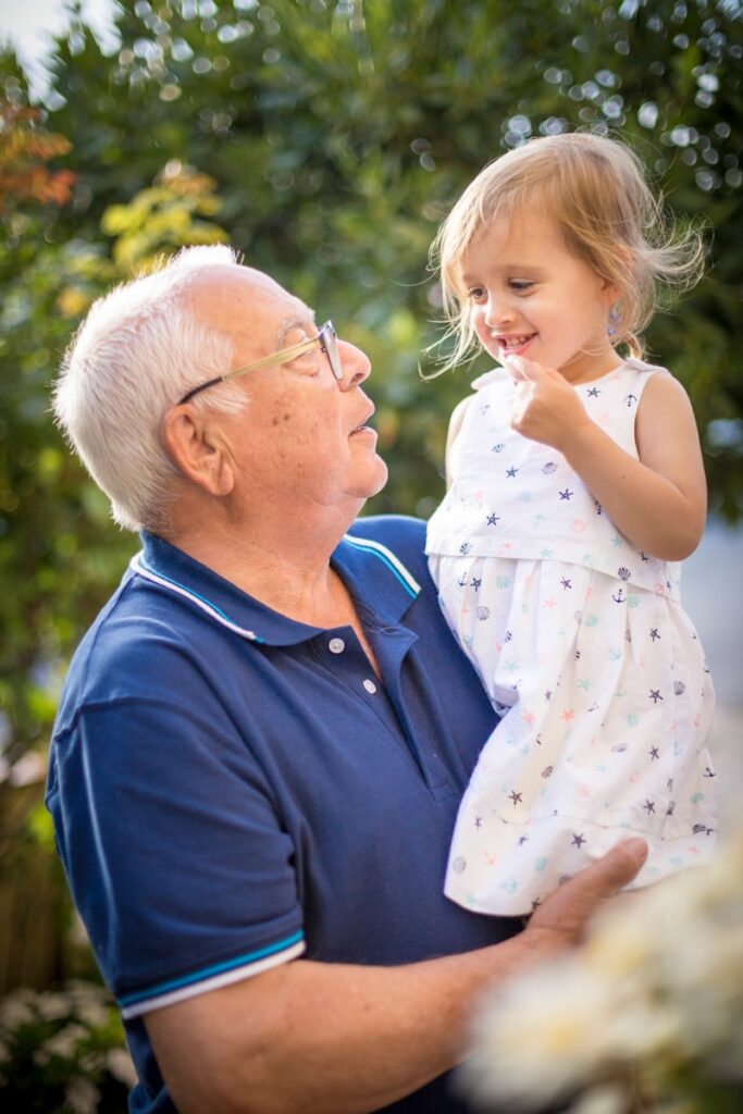 man in blue polo shirt carrying girl in white and pink floral dress
