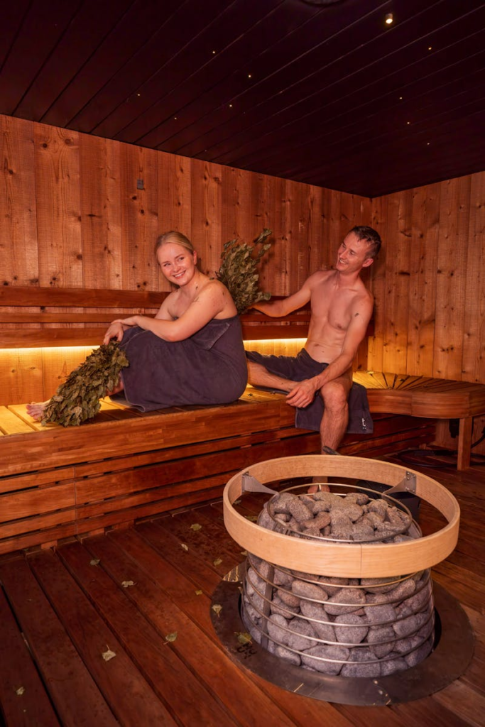 Two adults enjoying a traditional Nordic sauna experience with sauna whisking.