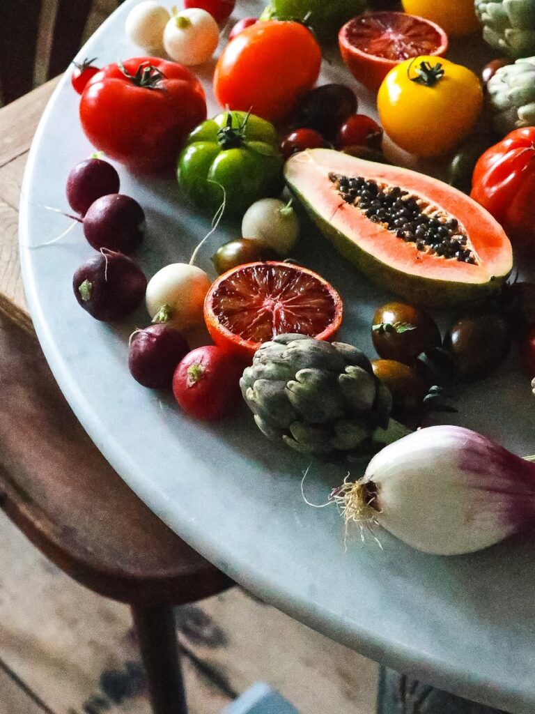 Bunch of various ripe exotic fruits and ripe healthy vegetables placed on marble table in light kitchen during harvest season