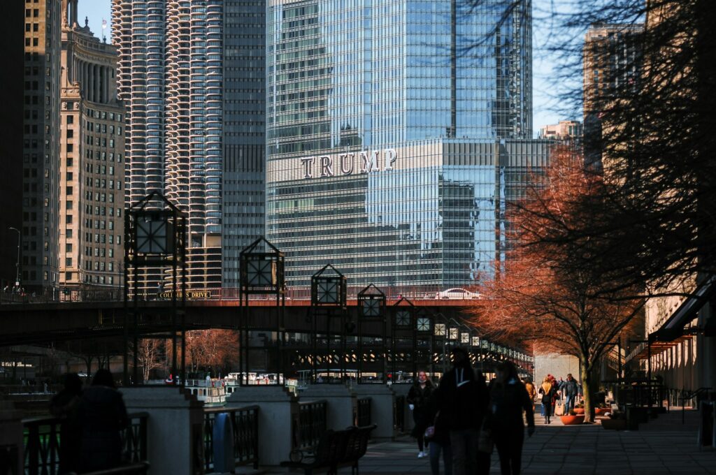 a group of people walking down a sidewalk next to tall buildings