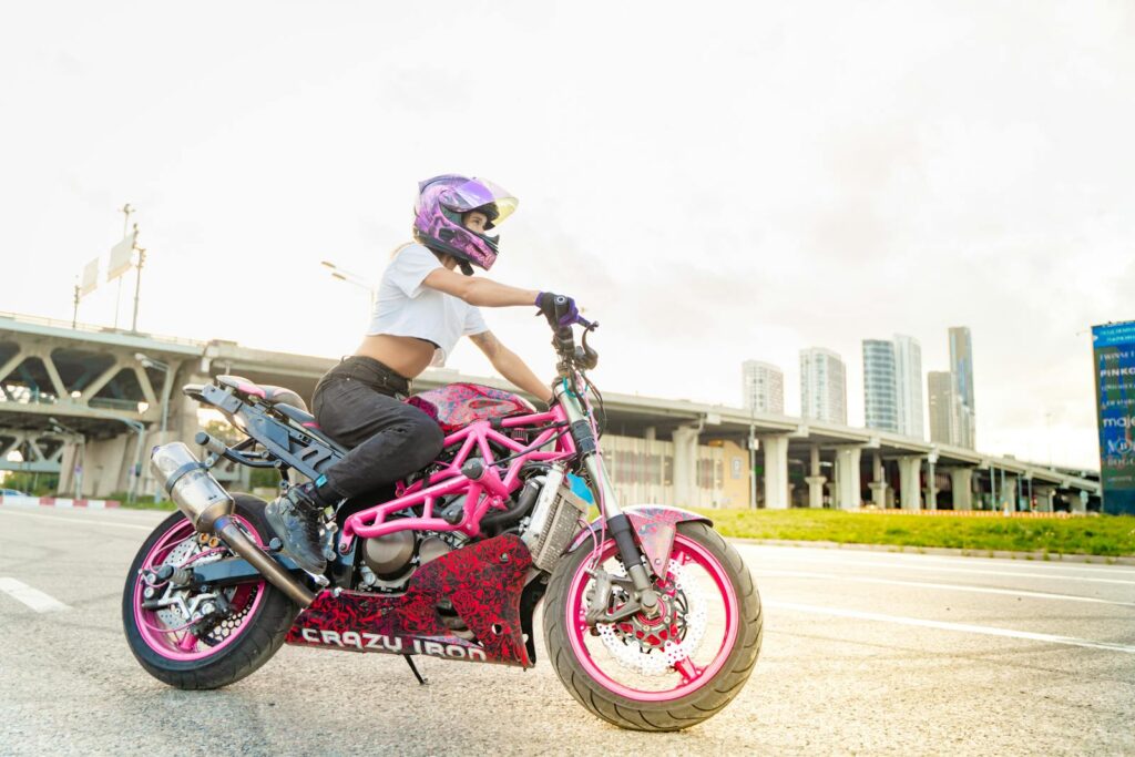Dynamic shot of a woman riding a custom motorcycle in an urban landscape, showcasing style and freedom.
