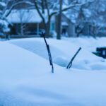 A serene winter scene in Toronto shows a car blanketed with snow on a quiet street.