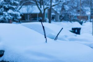 A serene winter scene in Toronto shows a car blanketed with snow on a quiet street.