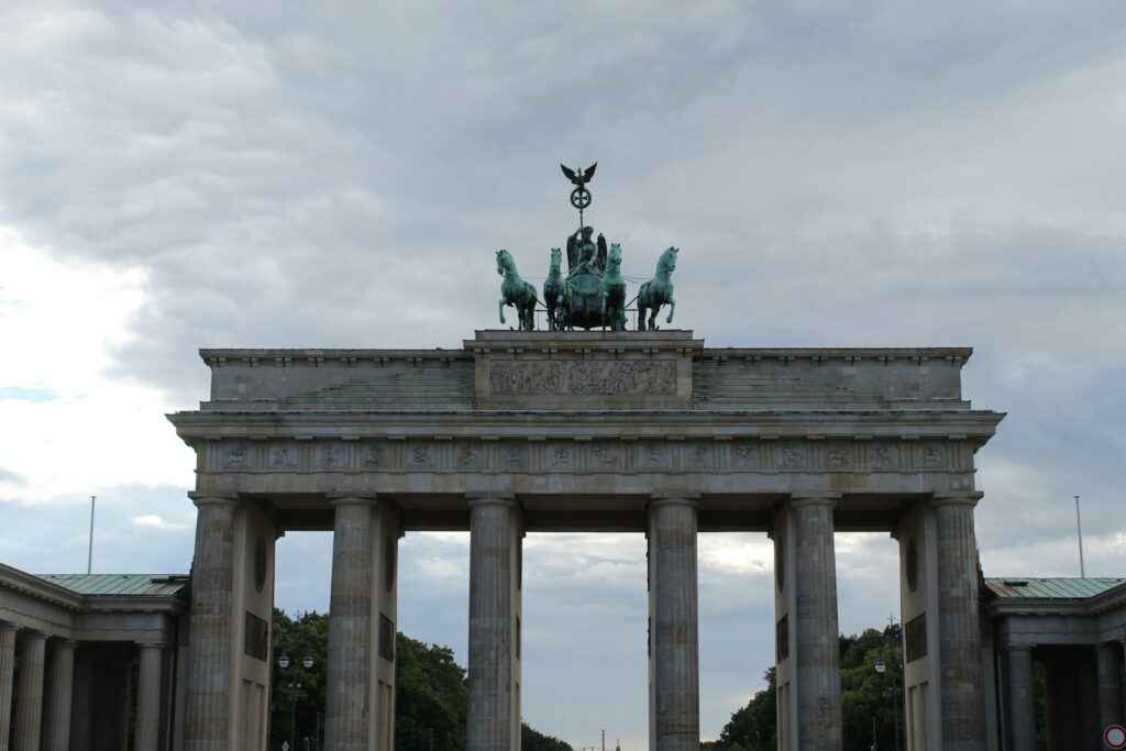 The brandenburg gate stands tall against the cloudy sky.