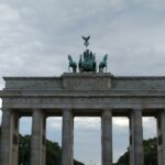 The brandenburg gate stands tall against the cloudy sky.