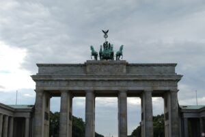 The brandenburg gate stands tall against the cloudy sky.