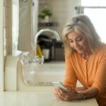 woman in orange long sleeve shirt using white smartphone